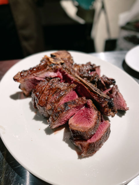 Plate covered in medium rare steak.