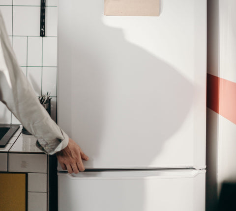Person going to open a modern white fridge.