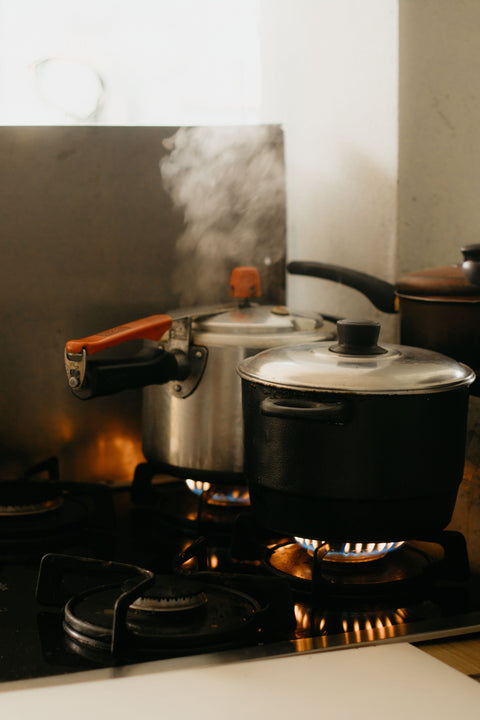 Two steaming pots on a gas stovetop.